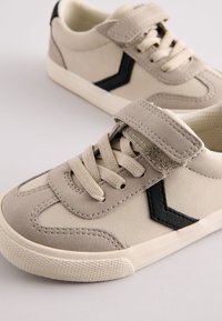 Beežid seemisnahast tennised musta ševroonimustriga, paelte ja takjakinnitusega, tekstureeritud kummist tallaga ning õmmeldud detailidega.