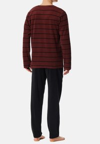 Camicia a maniche lunghe color bordeaux con strisce nere abbinata a pantaloni lounge neri, realizzati in tessuto morbido, con una vestibilità rilassata e un design semplice.