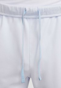 Světle modré sportovní šortky s texturovaným elastickým pasem a ladícími plochými šňůrkami. Hladká látka s pohodlným volným střihem.