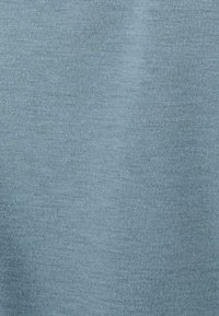 Tessuto azzurro chiaro con una trama liscia e uniforme, che presenta un sottile motivo a maglia senza dettagli accentuati o hardware.