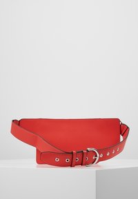 Borsa a cintura rossa in pelle con una texture liscia, forma rettangolare e una grande fibbia. Presenta un colore solido con bordi neri a contrasto.