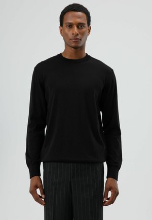 Zwart trui met lange mouwen en ronde hals, gemaakt van zachte stof, voorzien van geribbelde manchetten en een ontspannen pasvorm, gecombineerd met gestreepte pantalon.