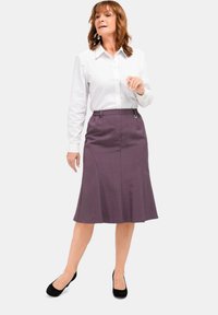 Lila knielange Rock mit ausgestelltem Design, strukturiertem Stoff und elastischem Bund. Kombiniert mit einem weißen Hemd mit Knöpfen und schwarzen Schuhen.
