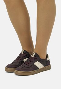 Sneakers bordeaux con tomaia in tessuto testurizzato, dettagli in pelle bianca, punta rotonda e suola in gomma. Presentano chiusura con lacci e un dettaglio con logo.
