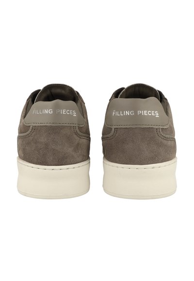 Bruna mockaskor med en strukturerad yta, vita gummisulor och en grå baksida som har varumärket "FILLING PIECES."