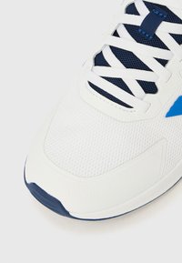 Scarpa sportiva bianca con dettagli blu, tomaia in mesh e suola in gomma. Presenta lacci bianchi e puntale con texture.