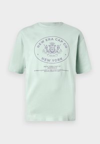 Mentová bavlnená tričko s krátkymi rukávmi. Obsahuje kruhové logo v tmavšej fialovej farbe s nápisom "New Era Cap Co" a "New York."