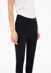 Zwarte leggings met een naadloze tailleband, met een gladde textuur en minimalistisch ontwerp. Materiaal zorgt voor flexibiliteit en comfort.