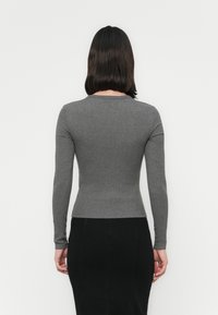 Gray long-sleeve top made of ribbed fabric, fitted shape with a round neckline, worn with a black pencil skirt. Plain design, no visible patterns.