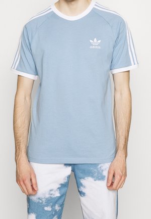 Light blue cotton t-shirt with white collar and sleeve cuffs, featuring three white stripes on shoulders and a small white logo on the chest.