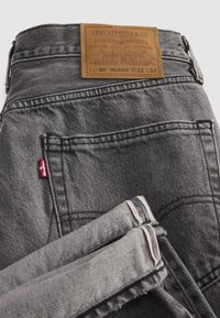 Γκρι τζιν Levi's 501 Relaxed που δείχνουν πίσω τσέπη, κόκκινη ετικέτα Levi's, δερμάτινο λογότυπο με μέγεθος W32 L32 και διπλωμένο τελείωμα με λεπτομέρεια selvedge.