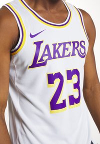 Weißes Basketballtrikot mit "LAKERS" in Lila und gelben Akzenten, Nummer "23" in großem Lila, umrissen in Gelb, und aus Netzstoff.