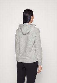 Grijze hoodie met een capuchon, geribde manchetten en een tailleband. Gladde textuur en casual ontwerp. Gekozen met zwarte leggings.