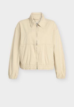 Béžová krátka bunda z mäkkej bavlnenej zmesi, s elastickými manžetami a pásom, predným zipsom a bočnými vreckami. Jednoduchý, čistý dizajn.