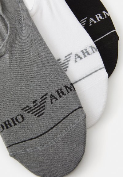 Tre paia di calzini alla caviglia in grigio, bianco e nero, con texture a coste e una fascia con il logo "ARM" stampato su ciascuno.