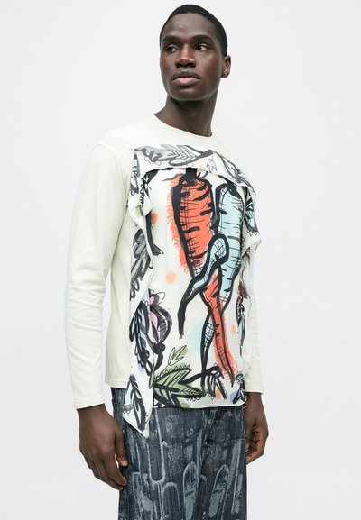 Πουκάμισο με μακριά μανίκια σε ανοιχτό κρεμ χρώμα, με μεγάλο γραφικό τύπωμα από πολύχρωμα λαχανικά και φύλλα, σε απαλό υφασμάτινο υλικό.