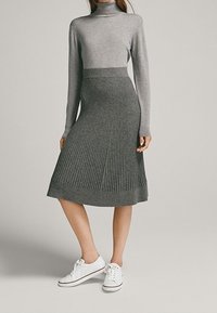 Gray knitted turtleneck sweater paired with a gray pleated skirt, both featuring a soft texture. Worn with white sneakers.