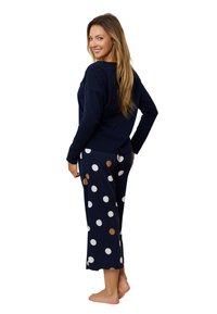 Granatowa bluzka z długim rękawem w połączeniu z granatowymi spodniami w białe i brązowe kropki, luźny krój, miękka struktura i krótsza długość.