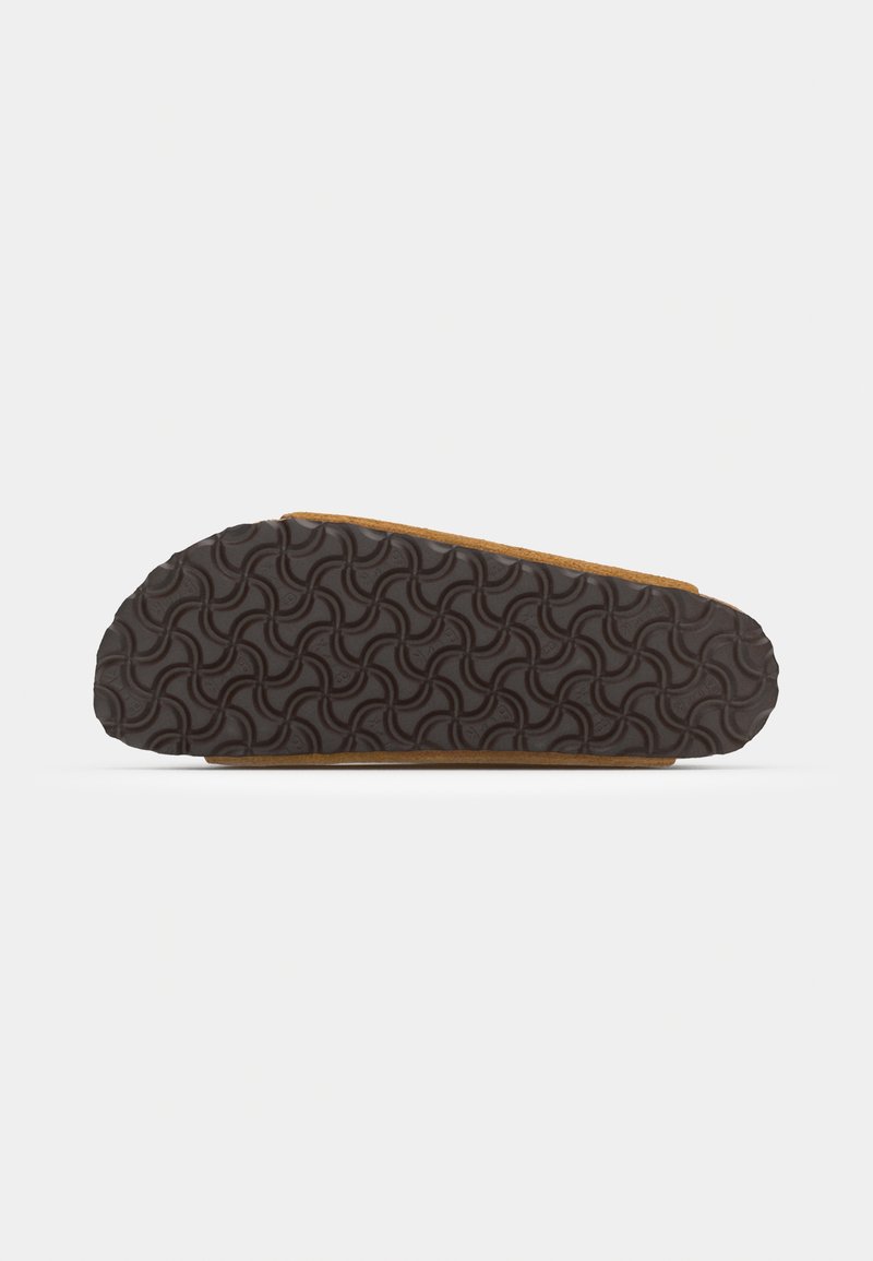 Chaussure brune à enfiler avec une semelle en caoutchouc texturée présentant un motif ondulé, un bord cousu contrastant et une tige en daim doux.