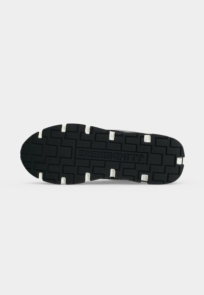 Semelle de chaussure noire avec des crampons profonds et des inserts en caoutchouc blanc, avec le nom de la marque "J.LINDEBERG" embossé au centre.