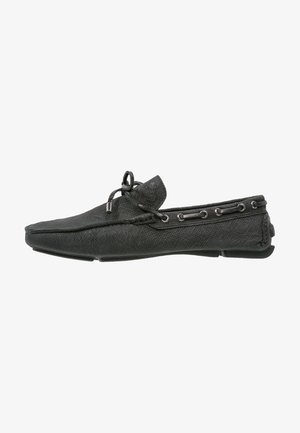 Schwarzer Mokassin-Schuh aus Leder mit strukturierter Oberfläche, Schnürdetails, einer runden Spitze und einer flachen Gummisohle.