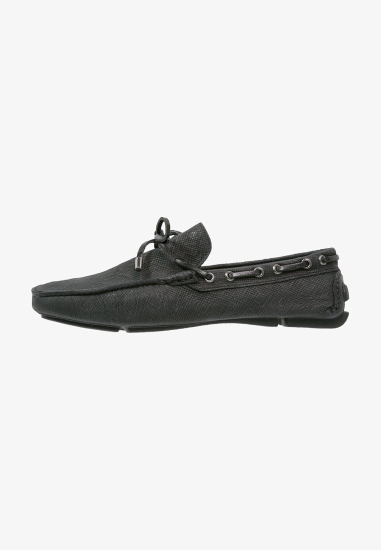 Mocassin en cuir noir avec surface texturée, accents de lacets, bout rond et semelle en caoutchouc profilée basse.