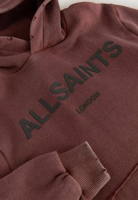 Bordo dukserica s kapuljačom od teksturiranog materijala, s crnim tiskanim logotipom "ALLSAINTS LONDON" na prednjem dijelu. Smanjen rukav i donji rub.