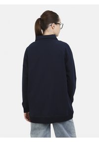 Felpa a maniche lunghe blu navy con colletto, polsini e orlo a coste. La vista posteriore mostra un tessuto liscio con una vestibilità leggermente ampia.
