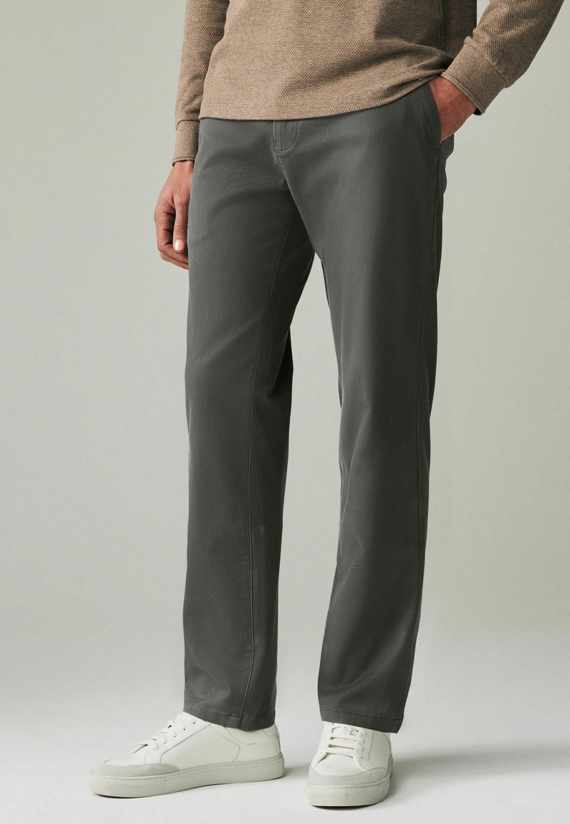 Grijze broek met een recht model, gemaakt van een zachte stof. Bevat twee achterzakken en is gecombineerd met witte sneakers.