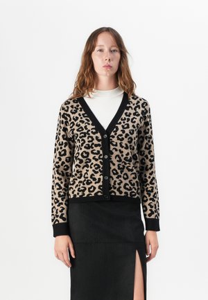 Leopardenmuster-Cardigan aus weichem Stoff, mit einem schwarzen V-Ausschnitt und Knöpfen, kombiniert mit einem schwarzen Rock mit seitlichem Schlitz.