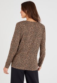 Leopardprint lange mouw top in bruin en zwart, met een gladde textuur en een relaxte pasvorm, voorzien van een ronde hals en een rechte zoom.
