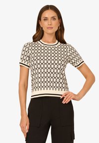 Gesticktes Kurzarm-Oberteil mit einer cremefarbenen Basis und schwarzem geometrischem Muster, geripptem Halsauschnitt und Saum. Schmale Passform, verkürztes Design, weiche Textur.