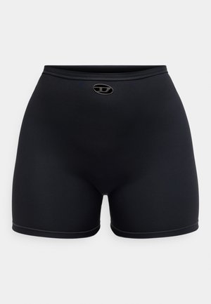 Pantalones deportivos negros hechos de un material elástico, con una pretina y un pequeño logotipo en el centro frontal. Textura suave, diseño ajustado.