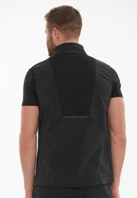 Svart ärmlös jacka med hög krage, med en mesh bakpanel och slät yta. Inkluderar kantiga designaccent och minimal metallisk detaljer.