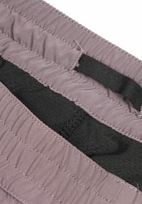 Elastischer Bunddetails auf lila Stoff mit gestepptem schwarzem Futter und kleiner schwarzer Stoffschlaufe.