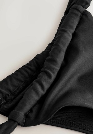 Melna bikini augšdaļa ar gludu audumu, salocītām malām un regulējamiem siksniņām. Tam ir bezšuvju dizains un maiga tekstūra ērtībai.