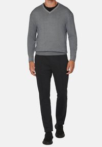 Šedý svetr s výstřihem do "V" a dlouhými rukávy, doplněný o černé texturované kalhoty a černé boty. Jednoduchý design, přiléhavý střih, hladký povrch látky.