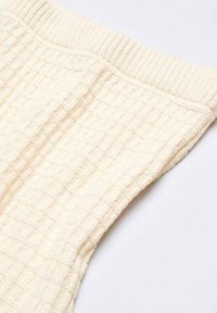 Tissu tricoté couleur crème avec un motif texturé en forme de grille. Doté d'une ceinture côtelée ; matériau doux et léger.