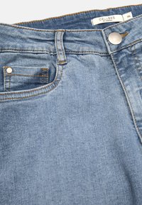 Ljusblå denimjeans med en framficka, silverknäppning och synliga sömnadsdetaljer längs midjan och fickorna.