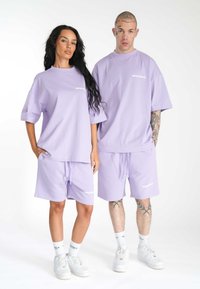 Lyse lilla bomuldsbeklædning bestående af oversized T-shirts og matchende shorts med snørelukning i waist. Logo detaljer på både T-shirts og shorts.
