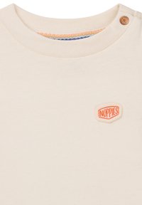 Crème katoenen T-shirt met een ronde hals, voorzien van een klein oranje geborduurd logo en een knoopdetail op de schouder. Gestructureerde stof.