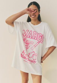 Vit oversized T-shirt med rosa grafiskt tryck av ett margaritaglas, ringar och texten "MARGS & Matrimony Bachelorette Club."
