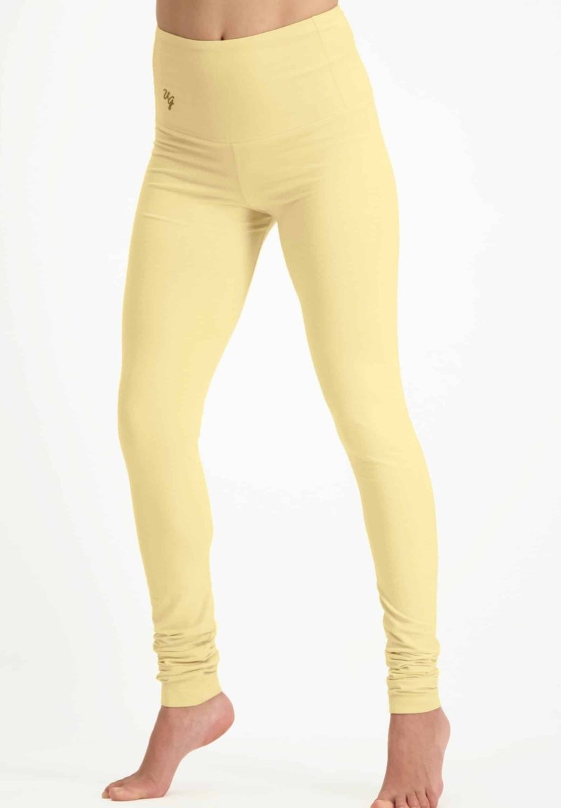 Geel leggings met een hoge tailleband, gemaakt van een rekbaar, glad materiaal. Heeft een geplooide textuur bij de enkels.