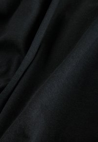 Čierna tkanina s hladkou textúrou, ktorá má jemný lesk a nenápadné záhyby, zdôrazňujúce jej ľahké a pružné vlastnosti.