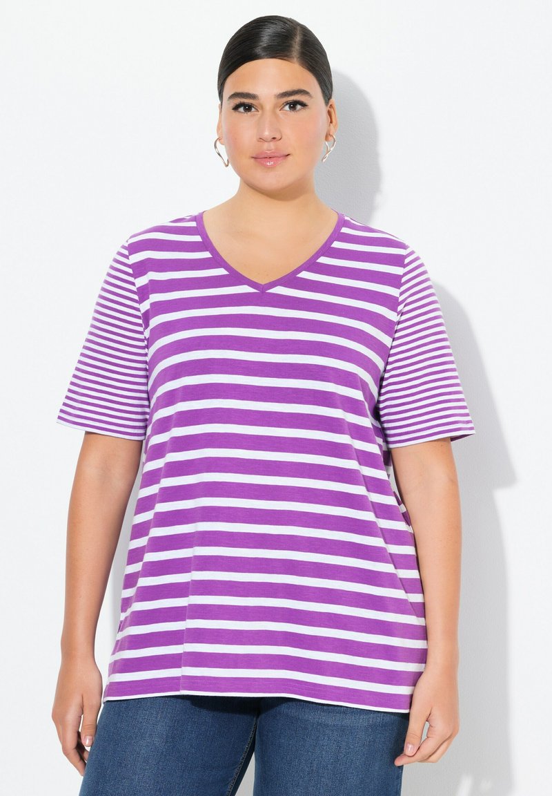 Camiseta de cuello en V a rayas moradas y blancas, con mangas cortas, hecha de una tela suave, de corte relajado, combinada con jeans azules.