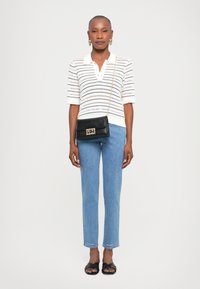 White textured polo shirt with short sleeves, light blue slim jeans, black crossbody bag with gold hardware, and black slide sandals.