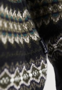 Strickpullover aus einer Wollmischung, mit geometrischen Mustern in Dunkelgrün und Schwarz sowie einem schwarzen Etikett mit der Aufschrift "Barbour". Weicher Griff.