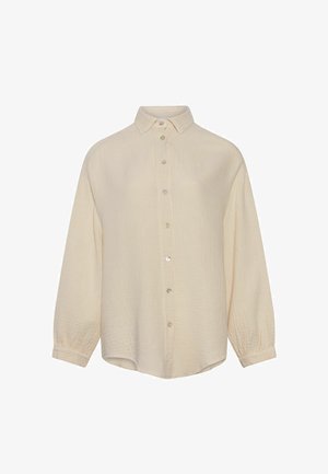 Chemise à manches longues couleur crème avec tissu texturé, col classique et poignets boutonnés, présentée sur un fond blanc.