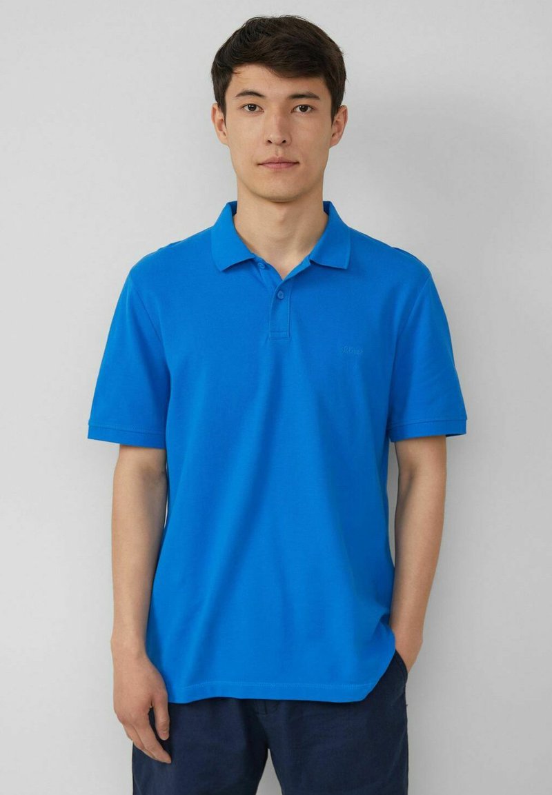 Blaues Poloshirt aus einer weichen Baumwollmischung, mit klassischem Kragen, kurzen Ärmeln und einem dezenten Logo auf der linken Brust.