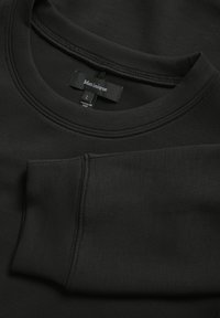 Čierna mikina s okrúhlym výstrihom, rebrovaným golierom a hladkou textúrou. Na etikete je nápis "Martinique," veľkosť L, s detailmi prešívania na rukávoch.